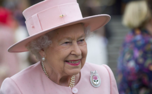 Regina Elisabetta II. La spilla piena di perle e l’abito in nuance “royal blue”