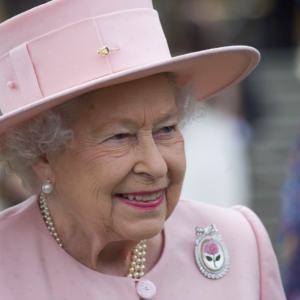 Regina Elisabetta II. La spilla piena di perle e l’abito in nuance “royal blue”